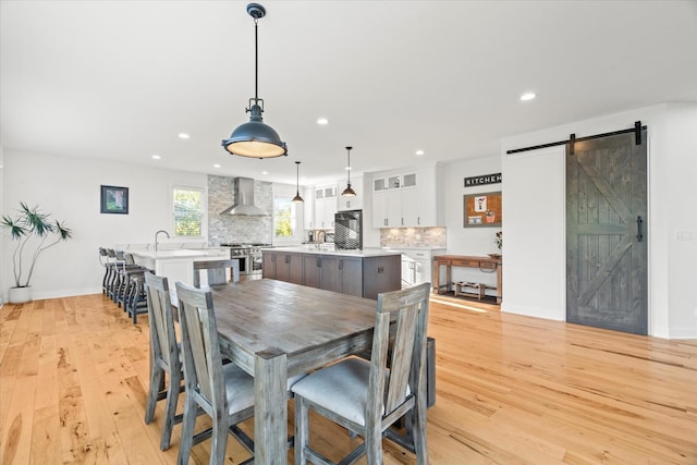 dining area featuring a barn door, sink, and light hardwood / wood-style flooring