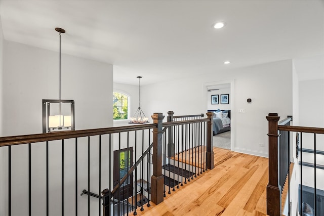 hallway with hardwood / wood-style flooring and an inviting chandelier