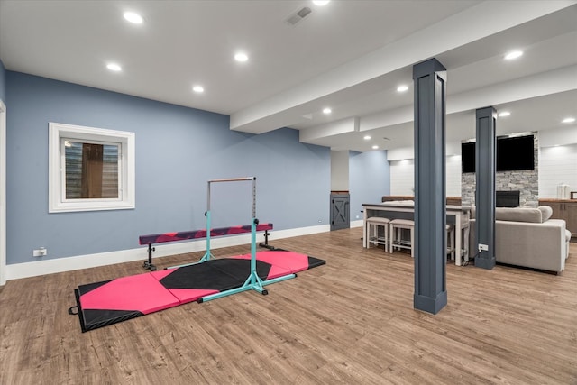 exercise area featuring light wood-type flooring and a fireplace