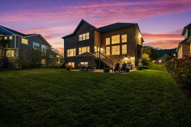 back house at dusk with a lawn and a patio area