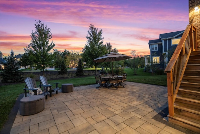 patio terrace at dusk featuring a lawn