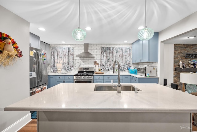 kitchen featuring sink, wall chimney exhaust hood, stainless steel appliances, tasteful backsplash, and pendant lighting