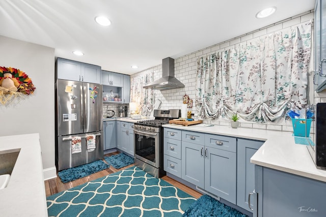 kitchen featuring tasteful backsplash, dark hardwood / wood-style flooring, stainless steel appliances, and wall chimney range hood