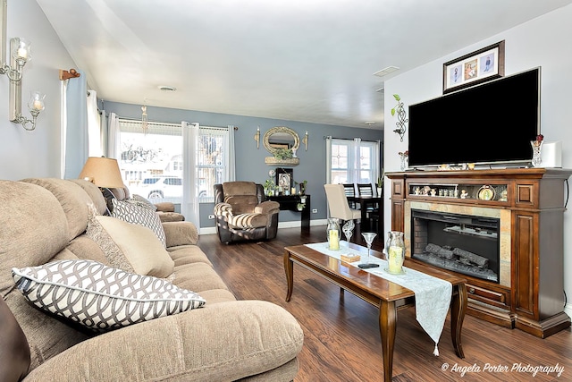 living room featuring a high end fireplace, dark wood-type flooring, and a healthy amount of sunlight