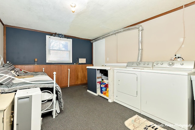 washroom with dark colored carpet, ornamental molding, a textured ceiling, washing machine and clothes dryer, and wood walls