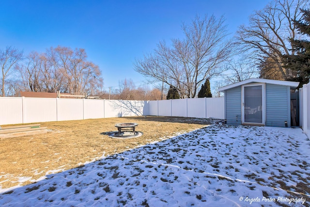 yard covered in snow featuring an outdoor fire pit and a shed