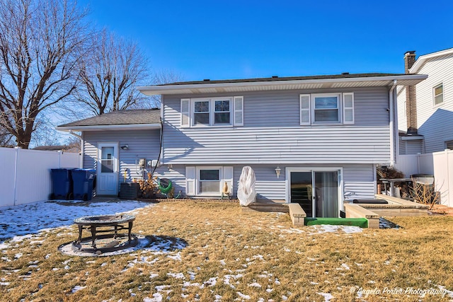 snow covered back of property featuring a yard and an outdoor fire pit