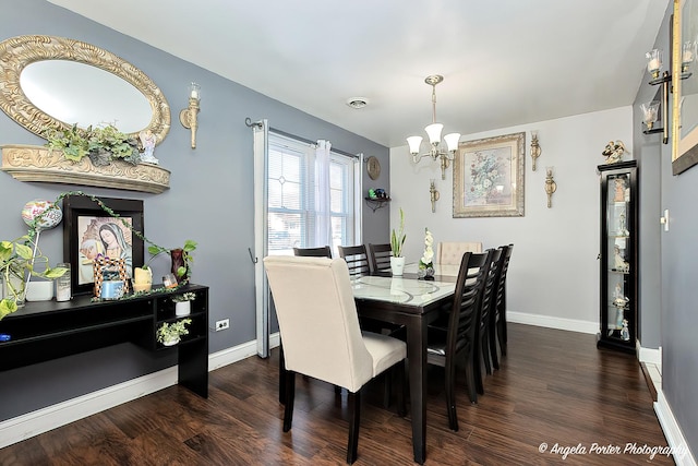 dining room with dark hardwood / wood-style flooring and an inviting chandelier