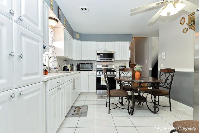 kitchen with sink, light tile patterned floors, backsplash, stainless steel appliances, and white cabinets