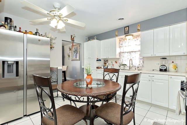 kitchen with stainless steel refrigerator with ice dispenser, light tile patterned flooring, white cabinets, and backsplash