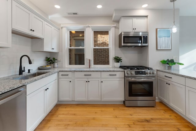 kitchen featuring light stone countertops, white cabinetry, sink, and stainless steel appliances