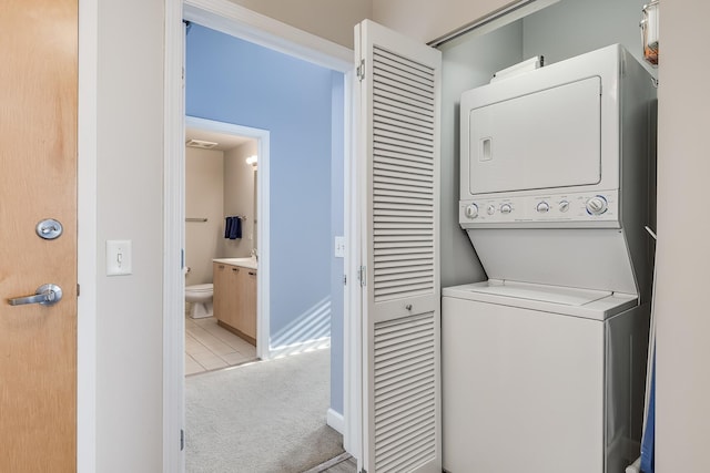 clothes washing area with light carpet and stacked washer / dryer