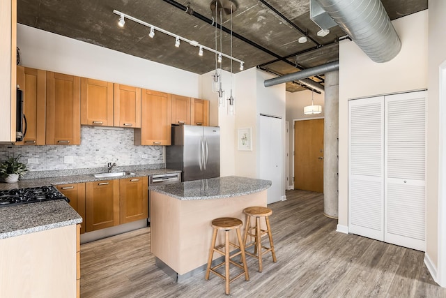 kitchen featuring a high ceiling, stainless steel refrigerator, a center island, sink, and decorative light fixtures