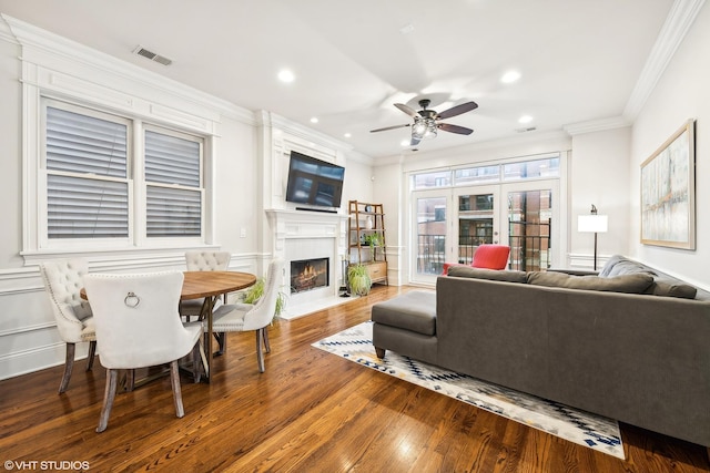 living room with a fireplace, hardwood / wood-style flooring, ceiling fan, and ornamental molding