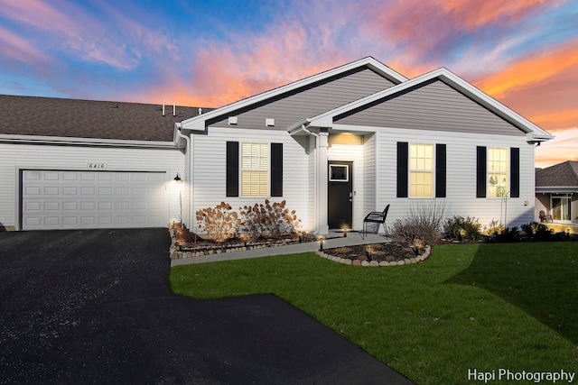 ranch-style house with a garage and a lawn