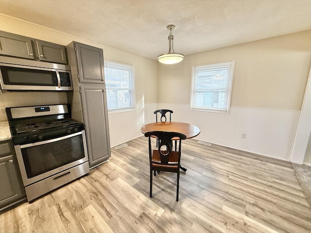 kitchen featuring stainless steel appliances, light hardwood / wood-style flooring, pendant lighting, a textured ceiling, and gray cabinets