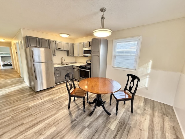 dining area featuring sink, light hardwood / wood-style floors, and a textured ceiling