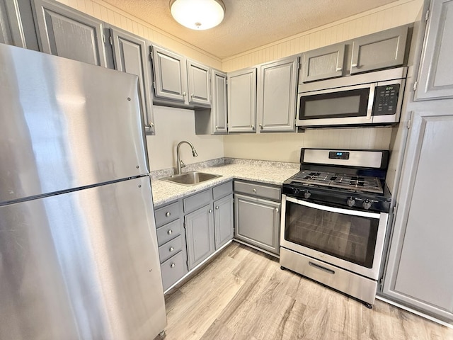 kitchen with gray cabinets, sink, a textured ceiling, and appliances with stainless steel finishes