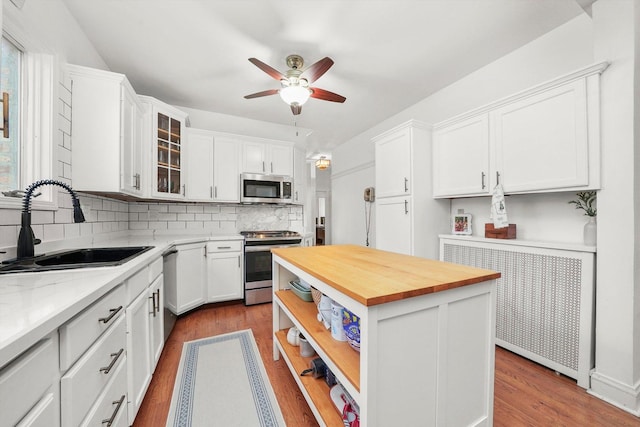 kitchen with white cabinetry, sink, backsplash, a center island, and stainless steel appliances