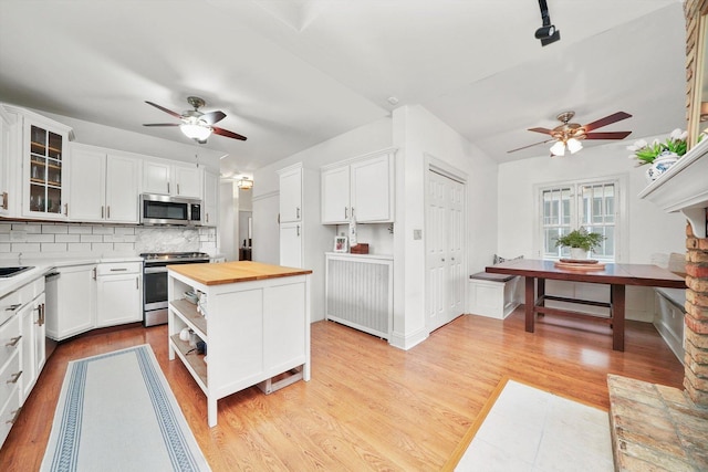 kitchen with butcher block counters, a center island, white cabinets, stainless steel appliances, and backsplash