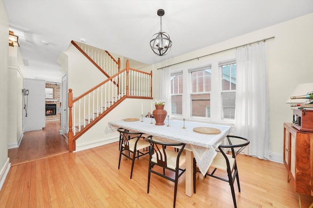 dining space with an inviting chandelier, a fireplace, and light hardwood / wood-style flooring