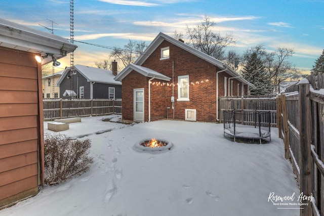 snow covered property with a trampoline and a fire pit