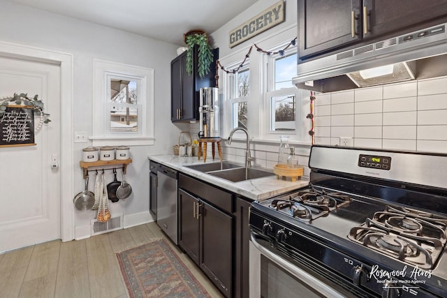 kitchen featuring dark brown cabinetry, sink, stainless steel appliances, and light hardwood / wood-style flooring