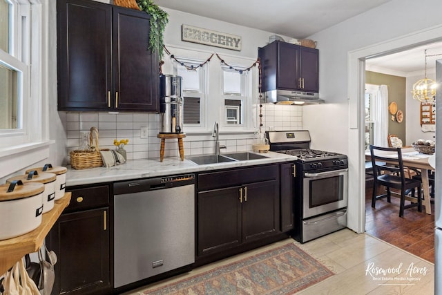 kitchen with decorative backsplash, sink, appliances with stainless steel finishes, and a chandelier