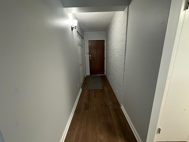 hall with dark wood-type flooring and brick wall