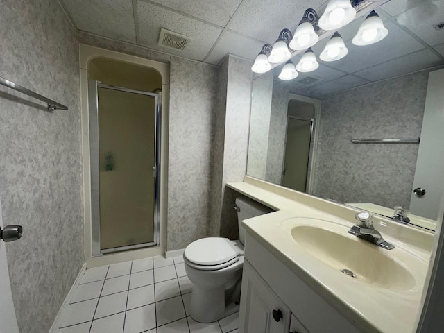 bathroom with tile patterned floors, walk in shower, a drop ceiling, vanity, and toilet