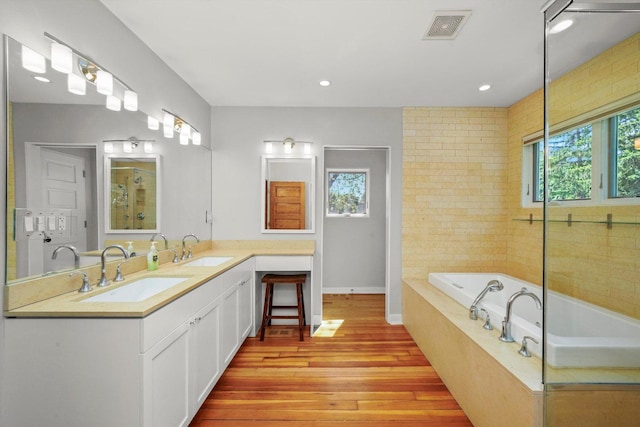 bathroom featuring tiled bath, hardwood / wood-style floors, and vanity