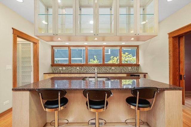 kitchen with a kitchen bar, tasteful backsplash, a kitchen island with sink, and sink