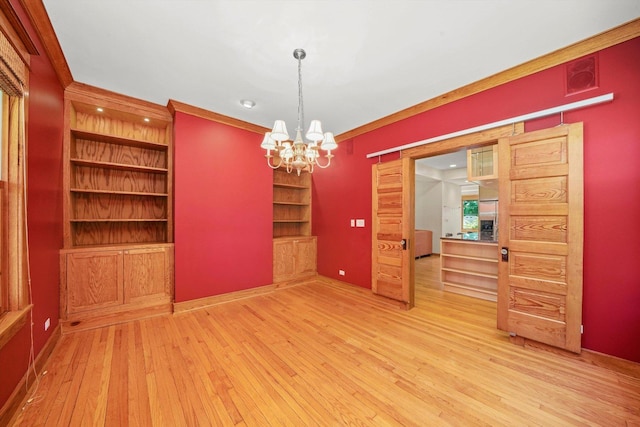 unfurnished dining area featuring hardwood / wood-style floors, crown molding, built in shelves, and a notable chandelier