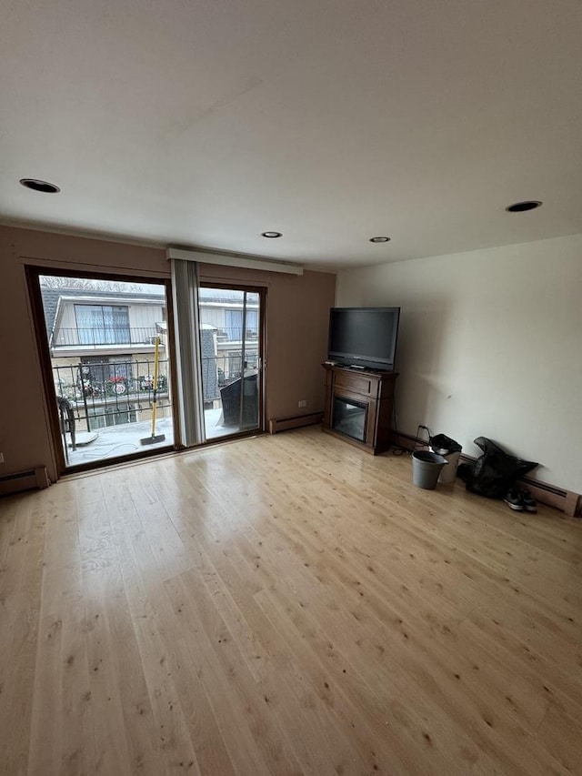 unfurnished living room featuring light hardwood / wood-style flooring and a baseboard heating unit