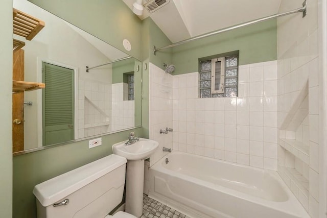 bathroom featuring tile patterned floors, tiled shower / bath combo, and toilet