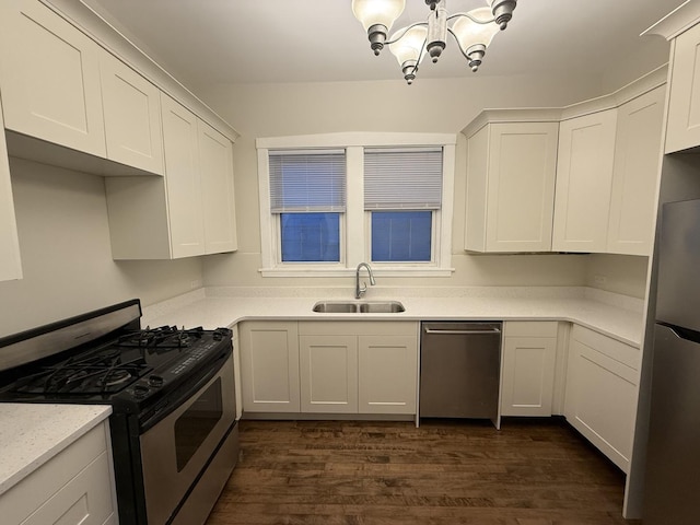 kitchen featuring dark wood finished floors, a chandelier, white cabinets, stainless steel appliances, and a sink