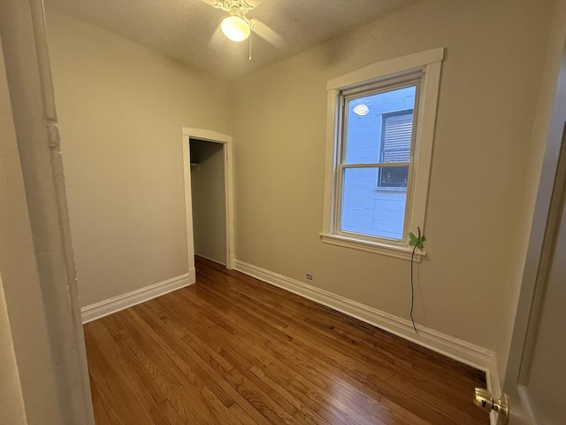 unfurnished bedroom with dark wood-style floors, a closet, and baseboards