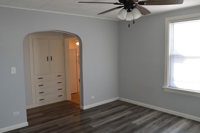 spare room with ceiling fan, plenty of natural light, ornamental molding, and dark wood-type flooring