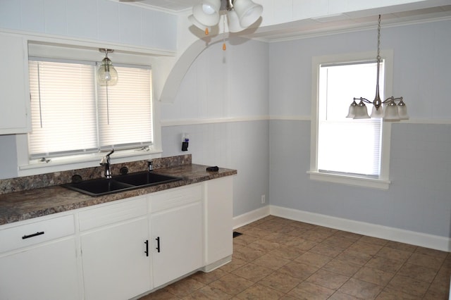 kitchen with sink, light tile patterned floors, crown molding, hanging light fixtures, and white cabinets