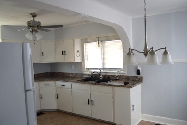 kitchen featuring white fridge, white cabinetry, ceiling fan, crown molding, and sink