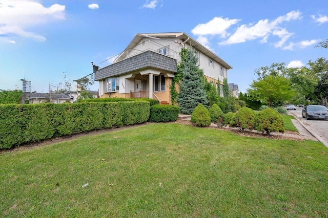 view of front facade with a balcony and a front yard