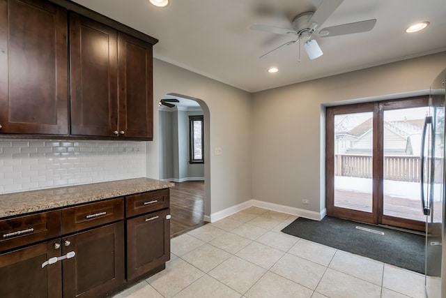 kitchen featuring tasteful backsplash, dark brown cabinetry, light stone countertops, and a healthy amount of sunlight