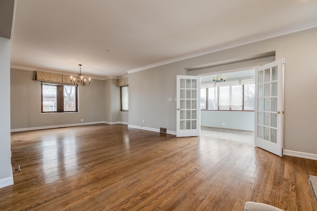 spare room with french doors, wood-type flooring, plenty of natural light, and a notable chandelier