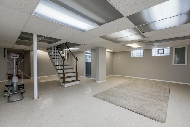 basement featuring a paneled ceiling and electric panel