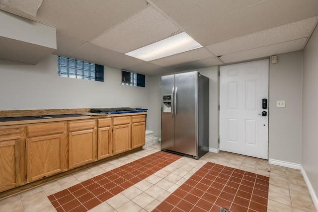 kitchen featuring stainless steel fridge with ice dispenser, a paneled ceiling, and tile countertops