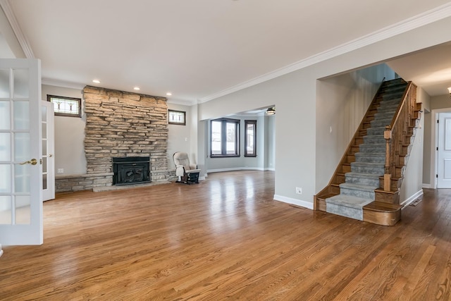 unfurnished living room featuring a stone fireplace, hardwood / wood-style flooring, french doors, and ornamental molding