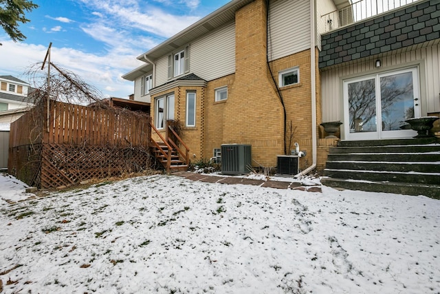 snow covered rear of property with central AC