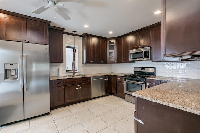 kitchen with ceiling fan, sink, light stone counters, dark brown cabinets, and appliances with stainless steel finishes