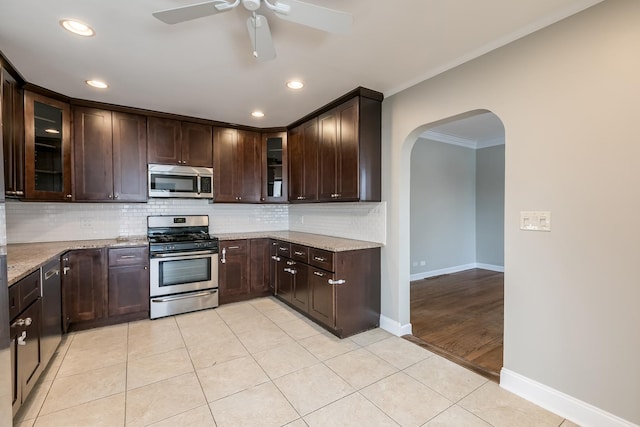 kitchen featuring light stone countertops, appliances with stainless steel finishes, ornamental molding, dark brown cabinetry, and light tile patterned flooring