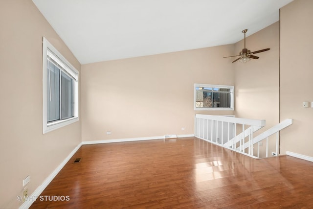 empty room featuring wood-type flooring, vaulted ceiling, ceiling fan, and a healthy amount of sunlight